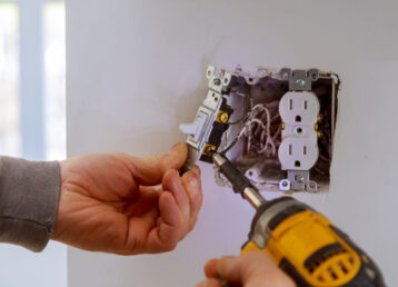 The hands of an electrician installing a power switch